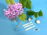 purple flowers in a vase with a spoon, spoons, and other tools