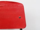 a red chair with a black seat on a white wall
