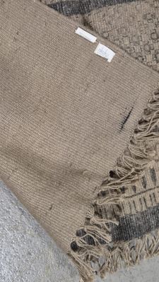 une photo d'un tapis de couleur marron et noir sur lequel est accrochée une étiquette