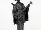 photographie en noir et blanc représentant la statue d'un homme tenant une guitare