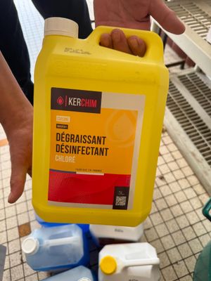 une personne tenant un flacon de produit dissuasif devant une pile de produits d'entretien