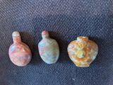 trois petits vases posés les uns à côté des autres sur une surface noire