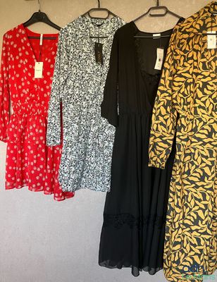 three dresses hanging on a rack in a room with clothes on hangers