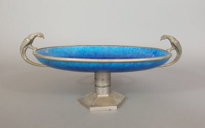 un bol en verre bleu à deux anses, posé sur un socle