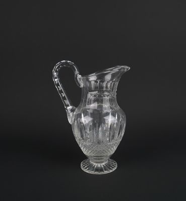 an antique glass pitcher with a handle on a black background