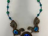 a necklace with blue glass beads and two birds on it