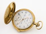 a gold pocket watch sitting on a white surface
