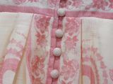 a close up of a pink and white dress with buttons