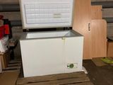 un congélateur coffre blanc posé sur une palette dans une pièce