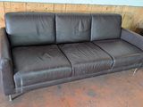 un canapé en cuir marron et deux fauteuils dans une pièce
