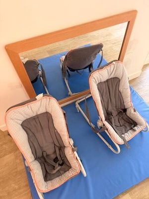 two baby chairs sitting on a blue mat in front of a mirror