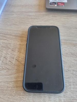 un téléphone portable noir posé sur une table à côté d'un ordinateur portable