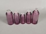 four purple bottles with white caps are lined up on a white surface