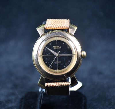 une montre en or avec un cadran noir posée sur un fond noir