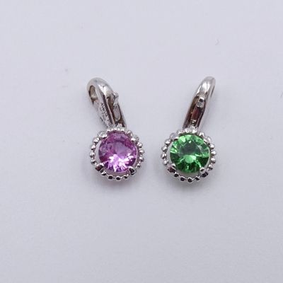 une paire de boucles d'oreilles en pierre violette et verte posées sur une surface blanche