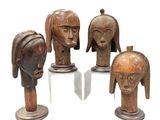 four wooden head sculptures of different shapes and sizes on a white surface