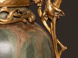 a green vase with a gold handle on a black background