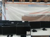many computer monitors sitting on a table in a warehouse
