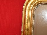 a gold framed mirror on a red wall in a room