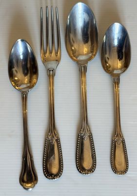 cinq cuillères en argent et une fourchette sont alignées sur une table