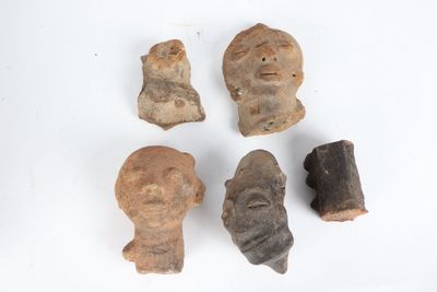 four pieces of clay with a face and a head on a white surface