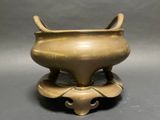 an old bronze incense pot with two horns on top of it