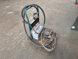 une machine posée à même le sol, à côté d'un tuyau d'arrosage