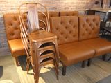 several chairs and a bench in a room with a brick wall in the background