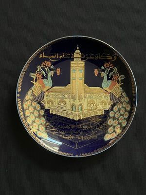 an image of a decorative plate with peacocks and a building in the background