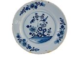 une assiette bleue et blanche ornée d'un oiseau et de fleurs