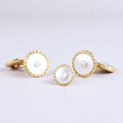 une paire de boutons de manchette dorés et blancs ornés de perles
