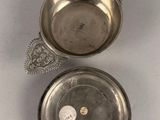 two silver dishes with a spoon and spoon rest on a white surface
