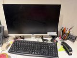 a computer monitor and keyboard on a desk with other office supplies