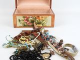 une boîte en bois remplie de bijoux variés, posée sur une surface blanche