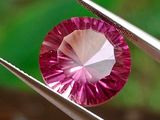 quelqu'un tient une pince dans laquelle est sertie un diamant rose