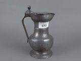 a small silver jug with a handle and handle on a gray background