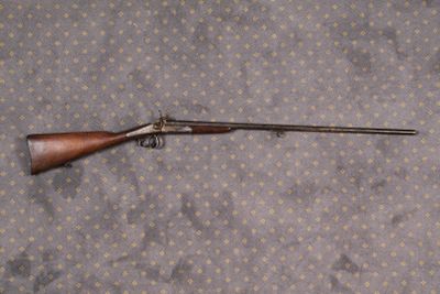 un vieux fusil au canon en bois posé sur un lit