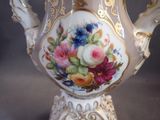 a white vase with flowers painted on it on a table