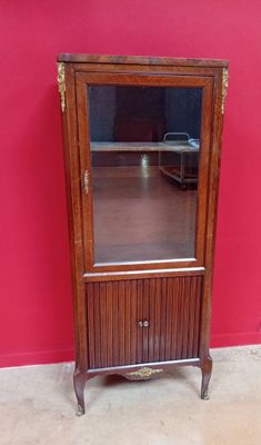une vieille armoire en bois surmontée d'un miroir, placée devant un mur rouge