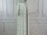 the back of a wedding dress on a mannequin stand in front of a white wall