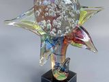 un gros plan d'une sculpture en verre représentant une fleur sur un socle noir