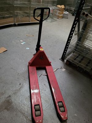 un chariot élévateur rouge posé au sol dans un entrepôt