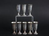 four silver wine glasses on a stand against a black background