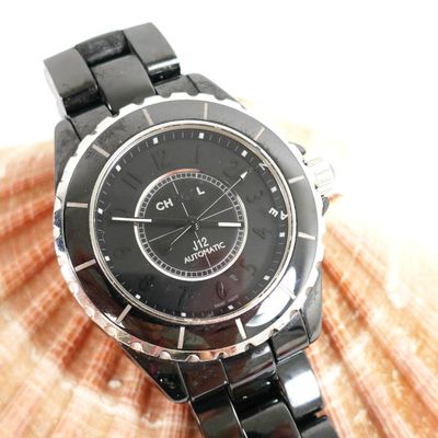 a black watch on a black bracelet on a seashell