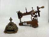 une petite machine à coudre posée sur une table, à côté d'une cloche