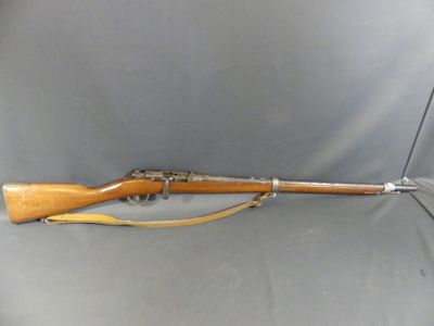a rifle that is sitting on a gray surface