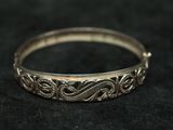 a close up of a silver bangle on a black cloth