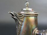 a silver coffee pot with a wooden handle on a table