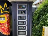 un distributeur automatique sur le côté duquel est posée une pizza