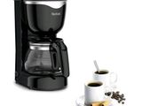 the coffee maker is next to a cup of coffee on a plate